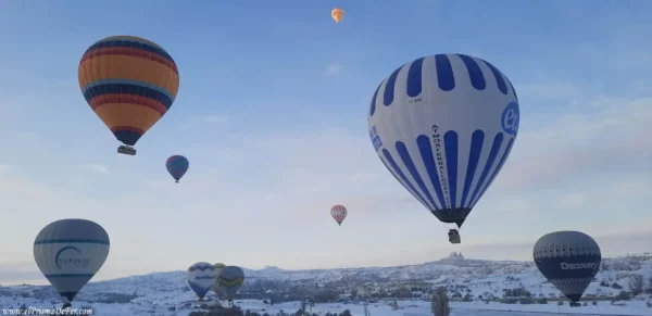 Paisaje nevado de Capadocia con globos volando