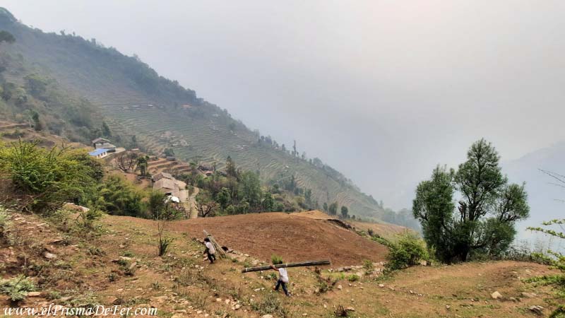 Camino a Chhomrong con gente trabajando y humo en el valle - Nepal