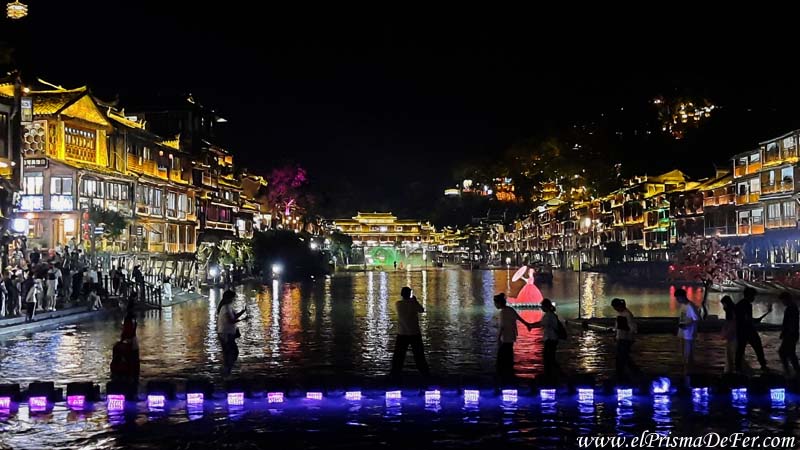 Puente hecho con losas en el río, lleno de gente sacando fotos